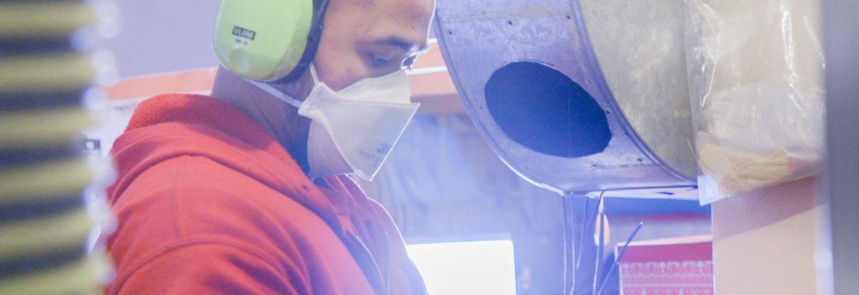 AtlasCare technician wearing a mask cleaning an air duct