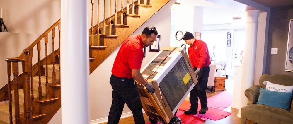AtlasCare technicians bringing in a furnace through a house
