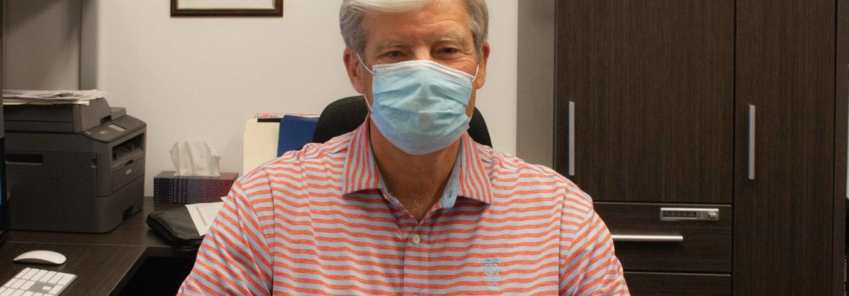 Roger Grochmal sitting in his office wearing a face mask