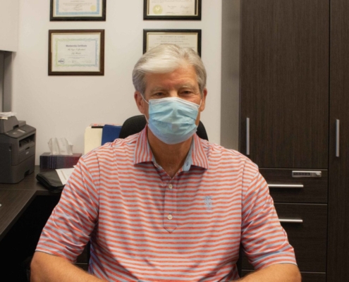 Roger Grochmal sitting in his office wearing a face mask