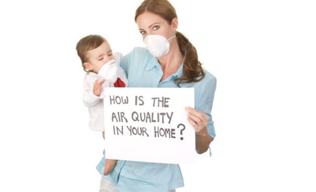 Woman and child wearing a face mask and holding an air quality sign